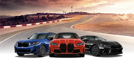 Three BMW High-Performance M vehicles parked near each other in front of a racetrack.
